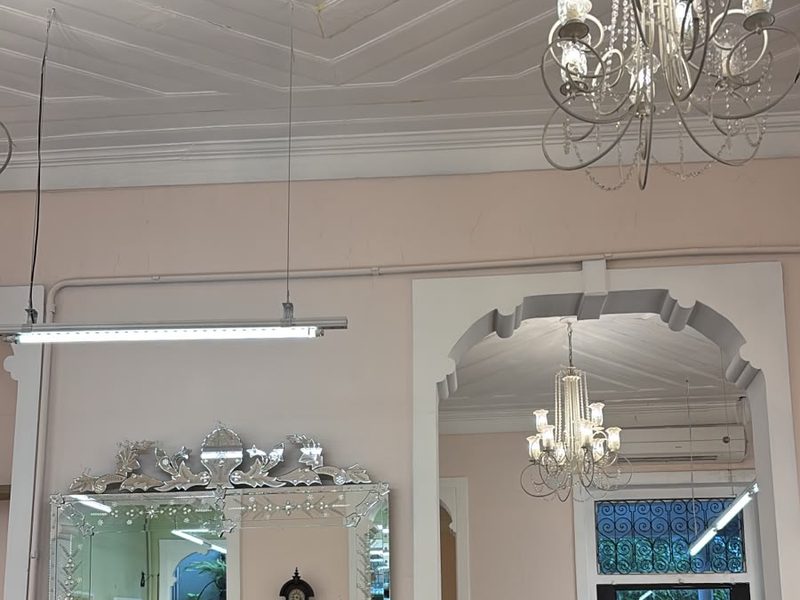 Salão principal do Constant Benjamin, com paredes rosa-claro, lustre de cristal e espelho veneziano