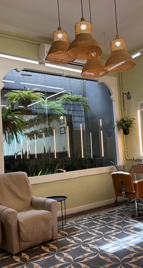 Canto do Constant Benjamin com luminárias de palha, janela para um jardim de samambaias e espelho iluminado